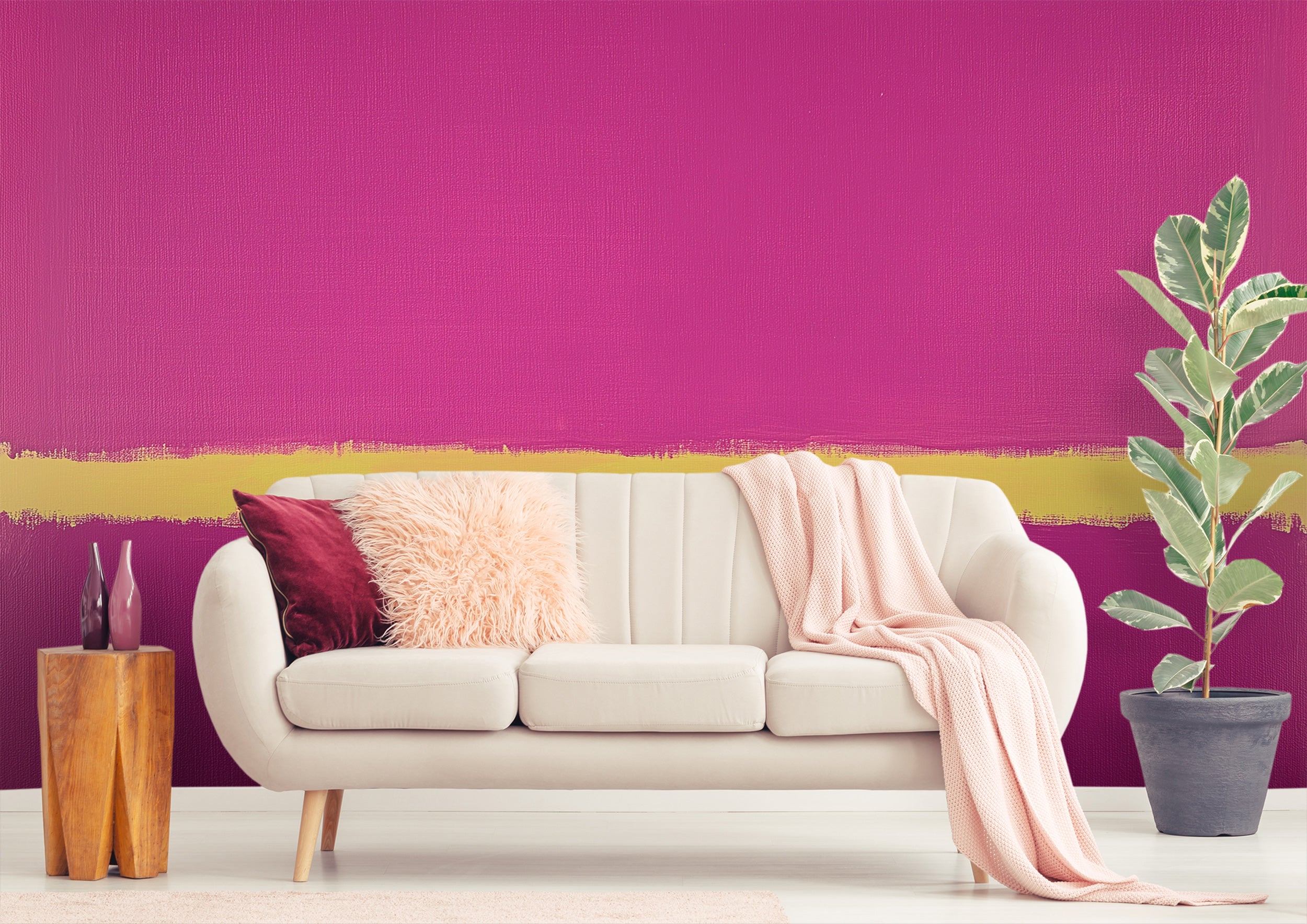 Pink abstract wall mural with magenta and gold brushstroke across a modern living room, white sofa, pink throw, and plant acc