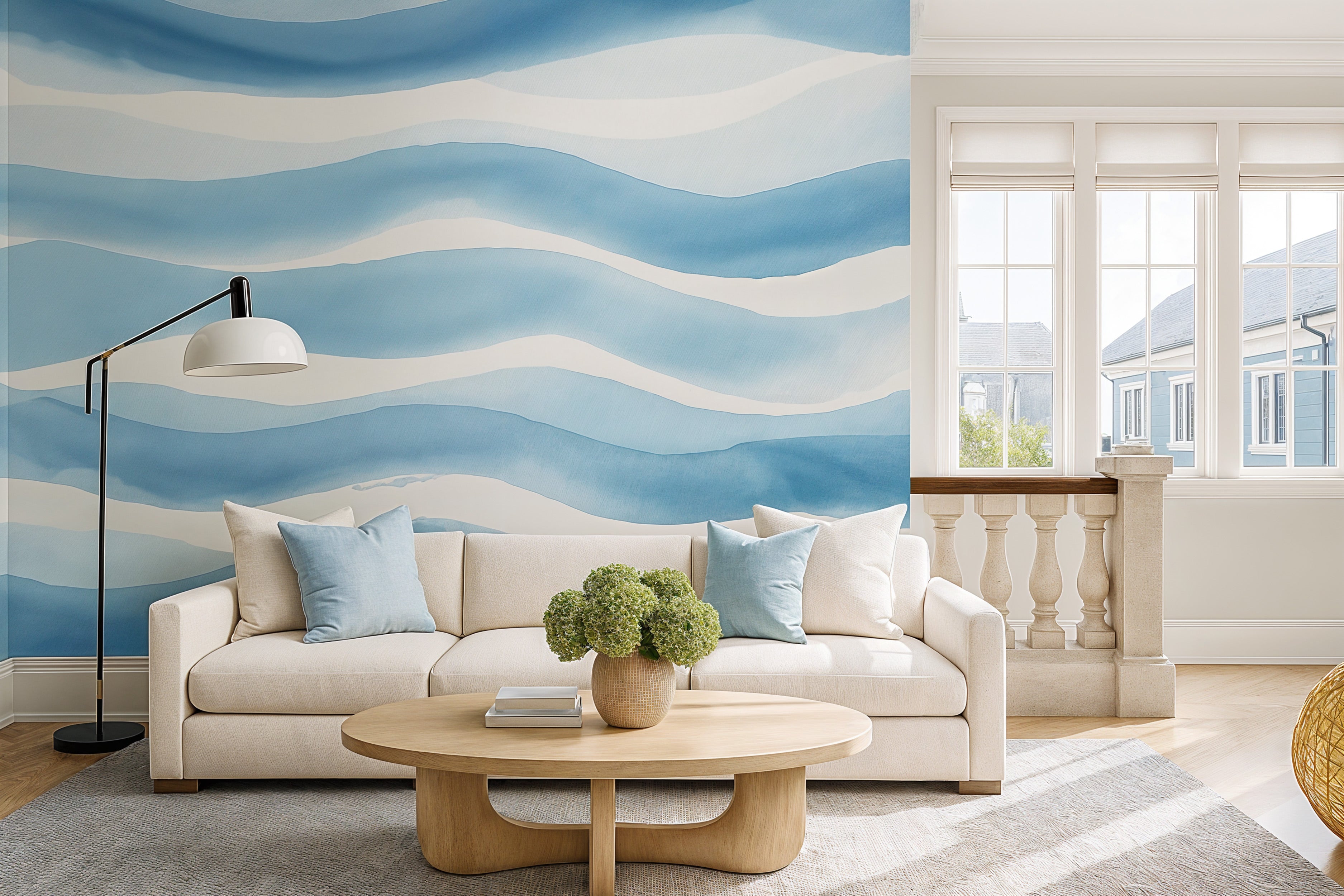 Blue abstract wave mural on living room wall with white sofa, light blue cushions, round wooden coffee table and large window