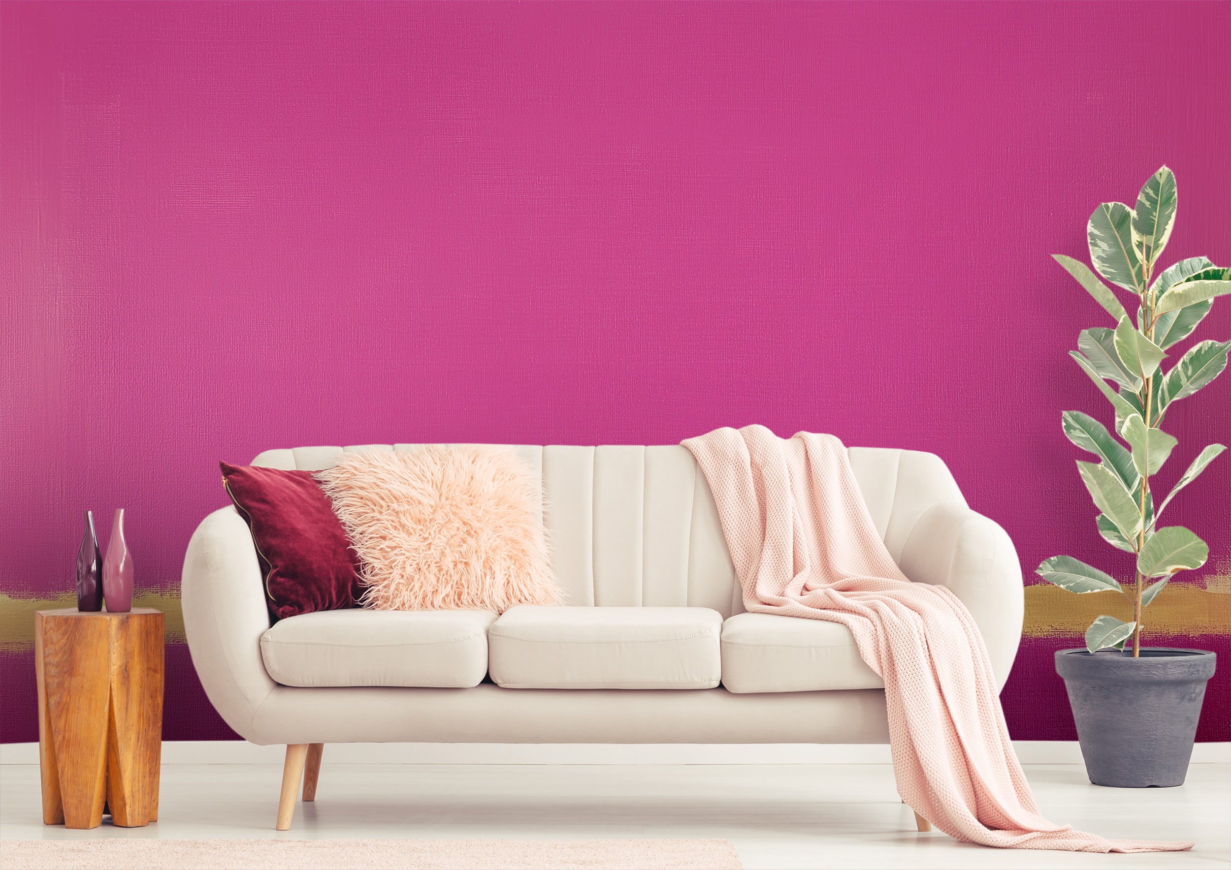Pink abstract mural with golden brushstroke accent in a chic living room featuring a beige sofa, pink pillows, soft throw, an