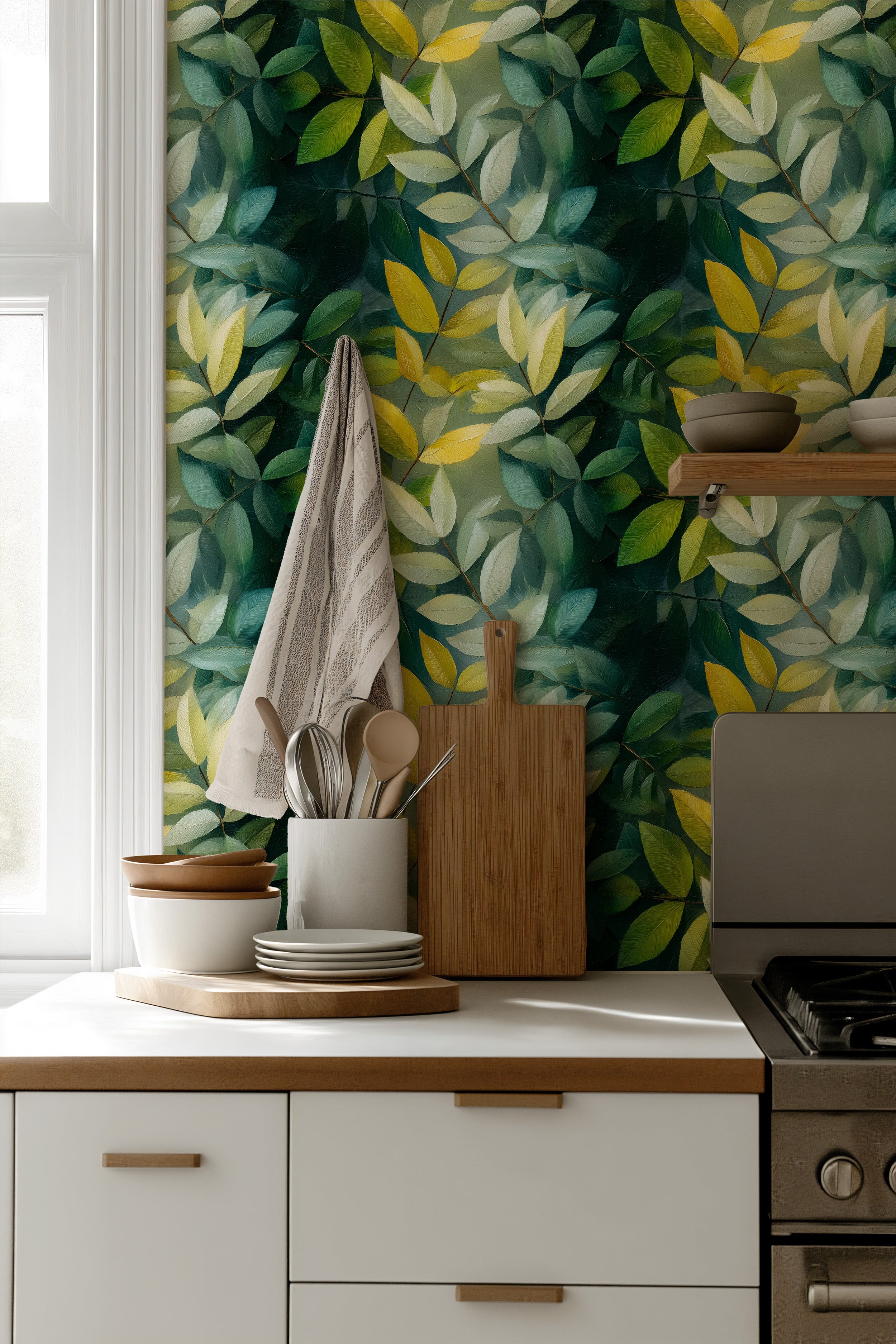 Vibrant green leafy botanical wallpaper in a bright kitchen with white cabinets, wooden utensils and a stainless stove