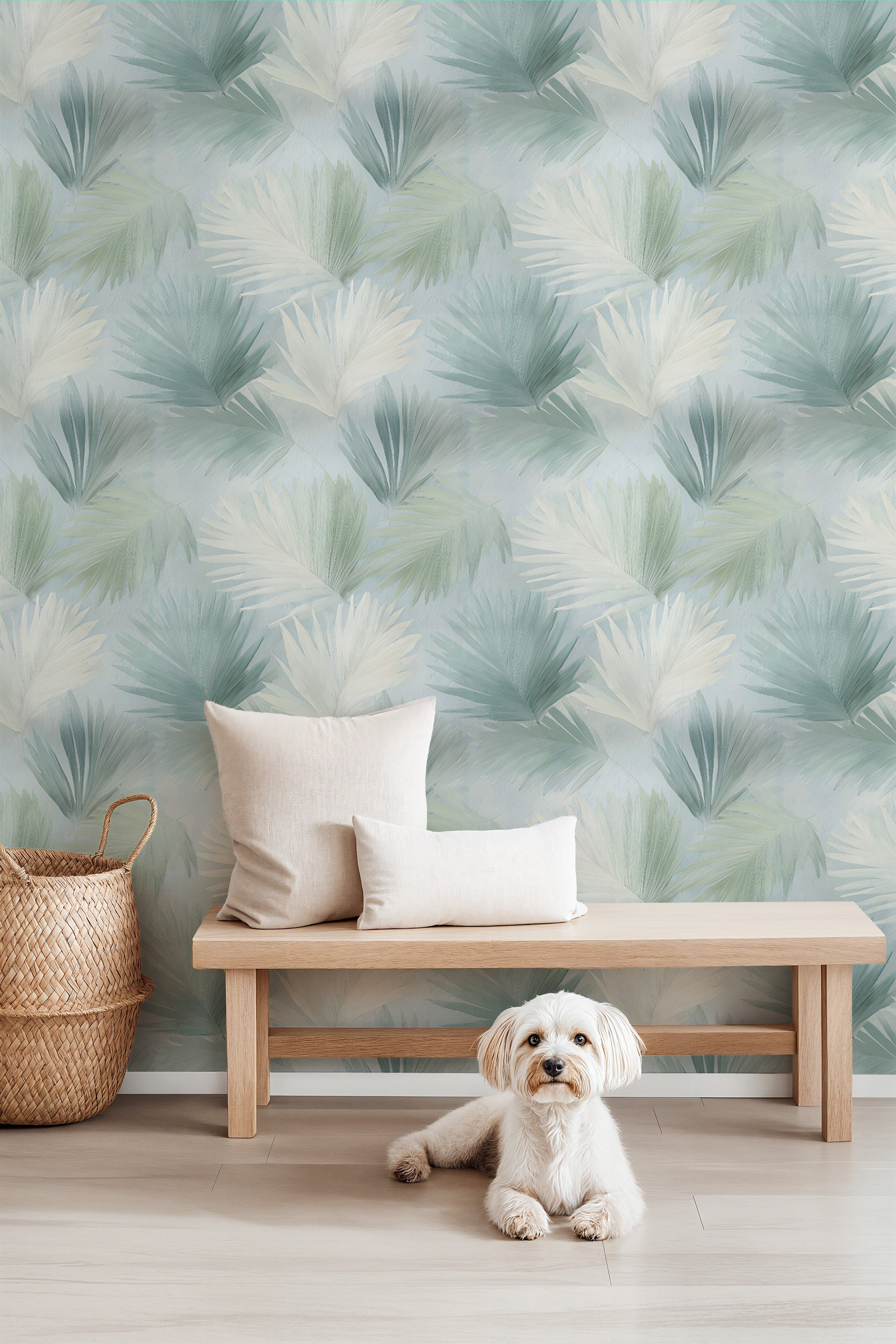Tropical palm leaves wallpaper in sage green and cream tones on a living room wall with a wooden bench and neutral cushions