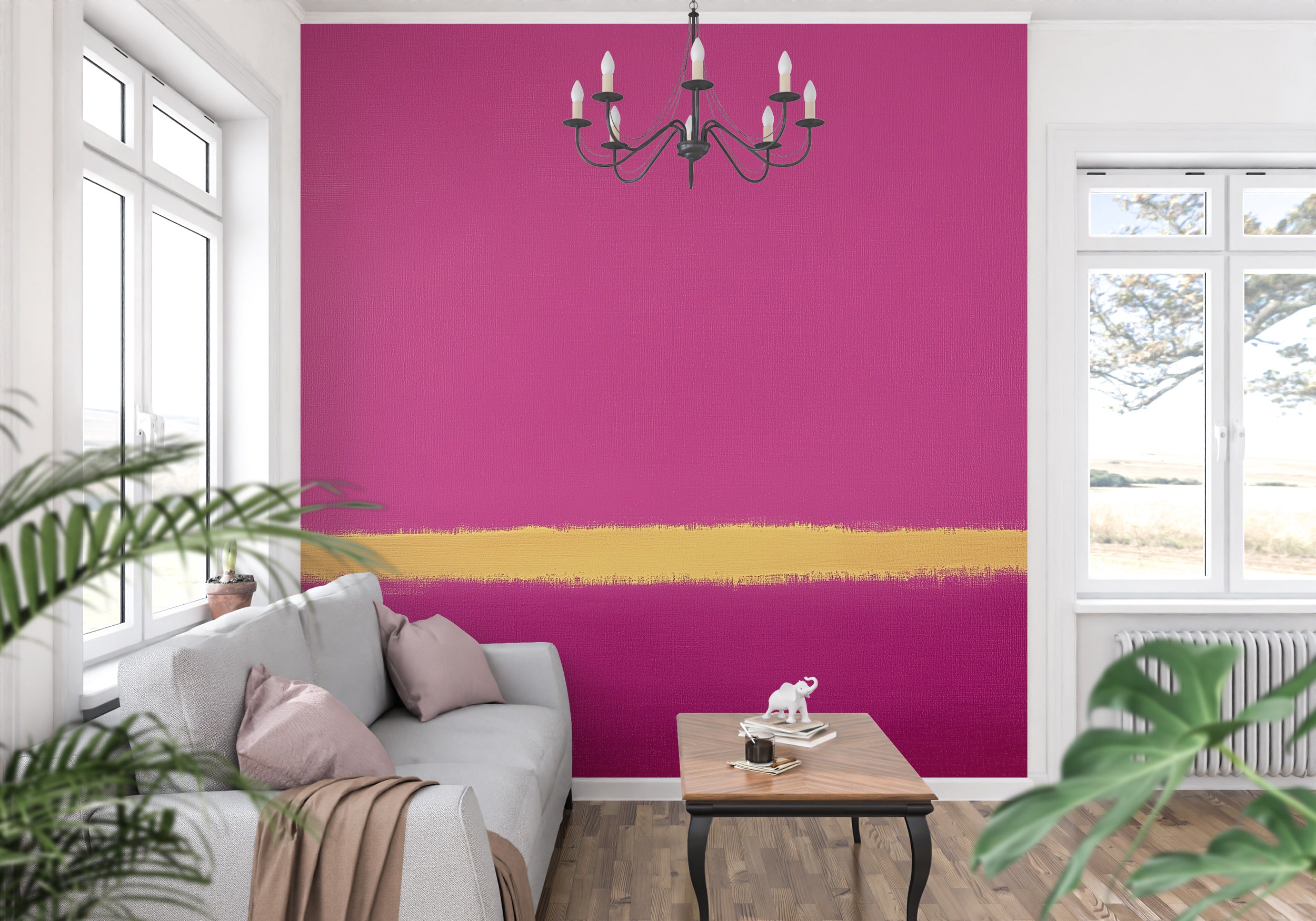 Pink and magenta abstract wall mural with a bold gold brushstroke across a bright wall in a modern living room with a chandel