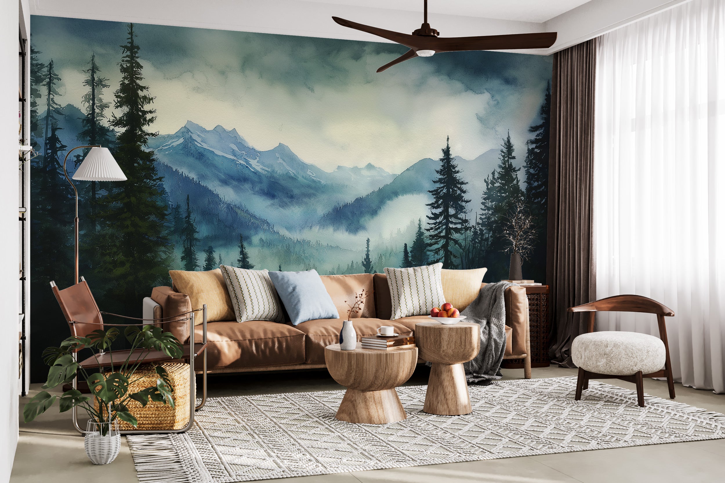 Watercolour mountain forest mural in a cozy living room with a brown sofa, neutral cushions, round wooden tables, and large f
