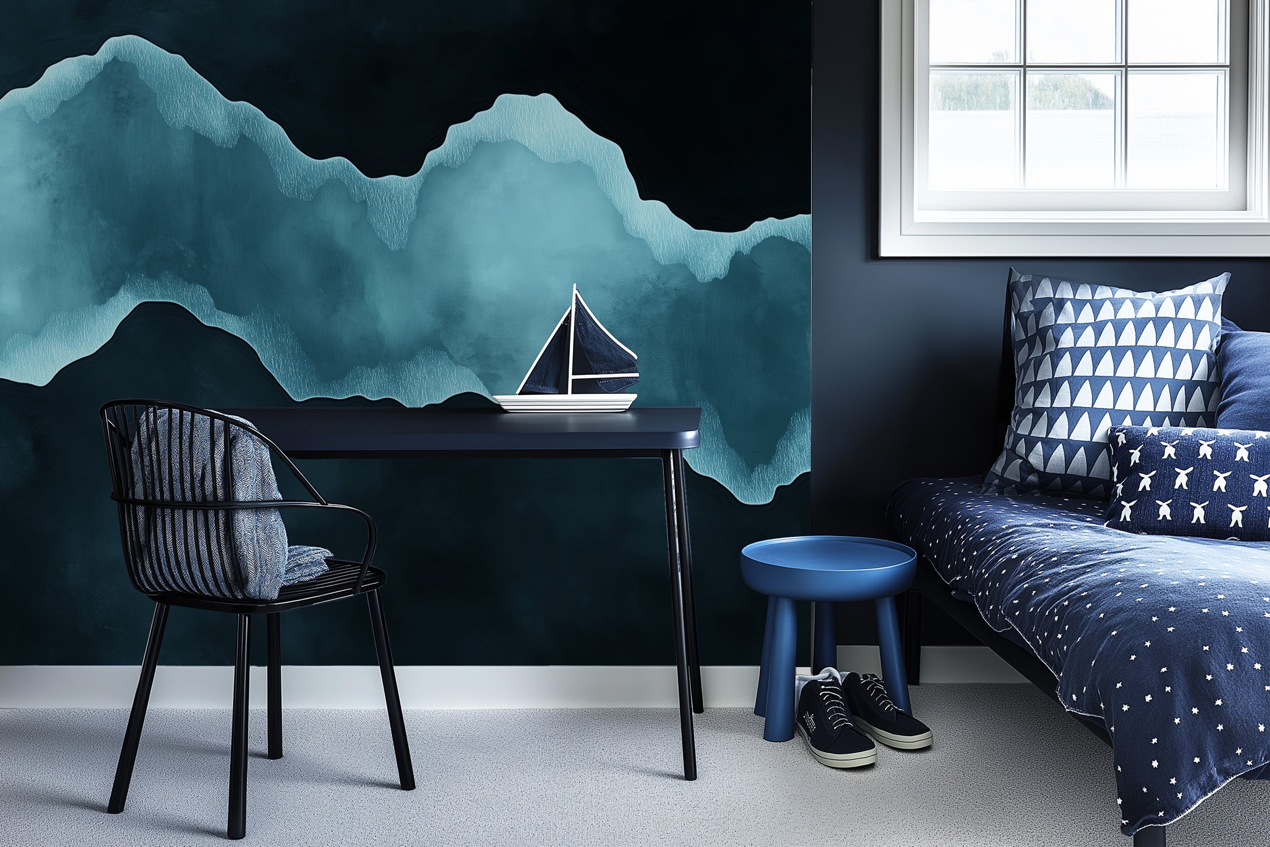 Abstract teal mountain mural in a modern navy bedroom with a desk, black chair, blue stool, and sailboat decor beside a daybe