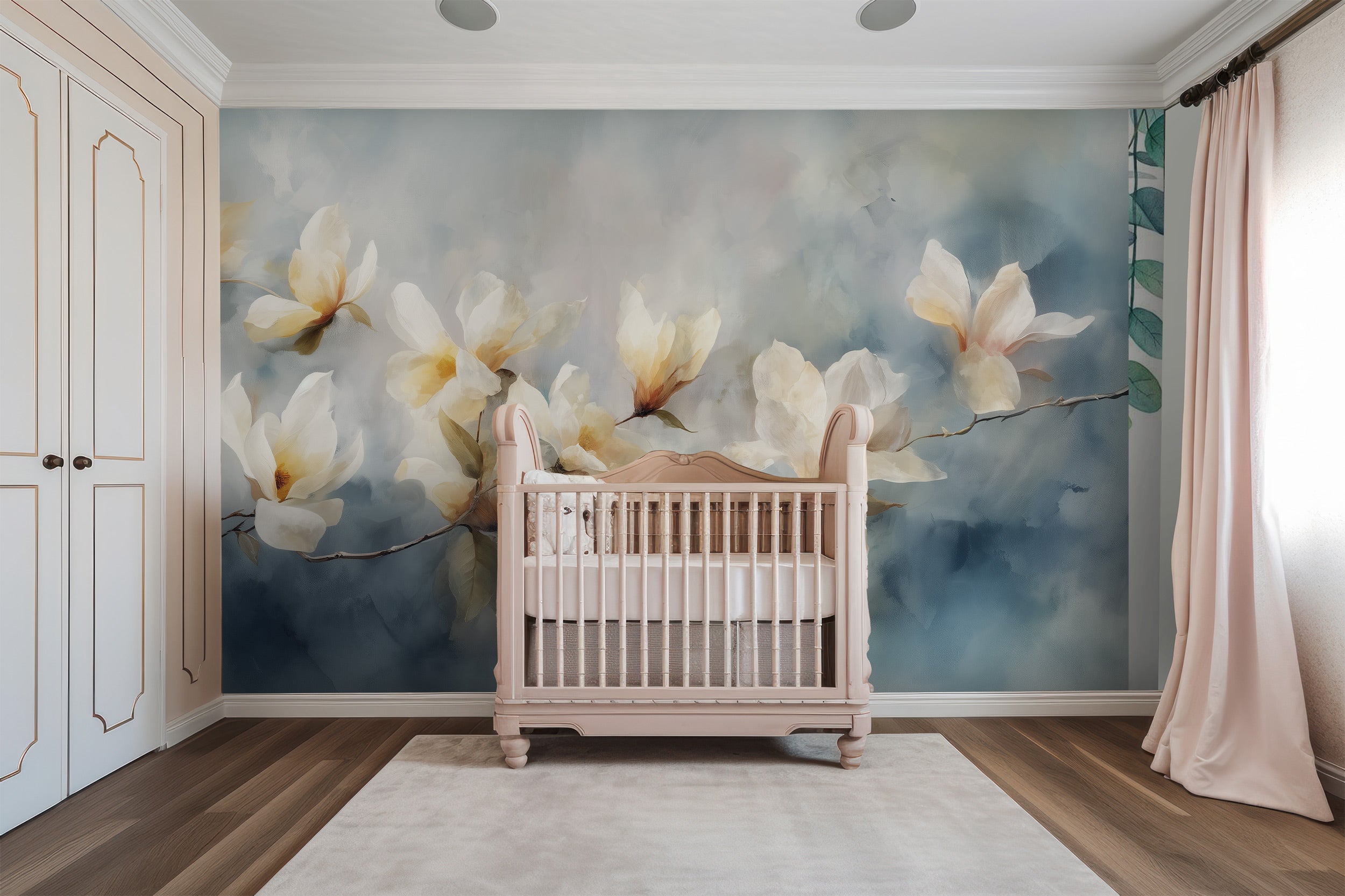 Watercolor magnolia branch mural in a pastel nursery with a pink crib, soft blue background, cream wardrobes, and light drape