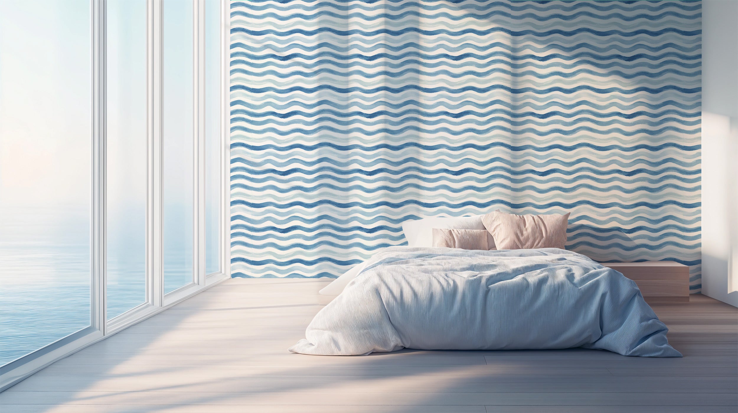Blue watercolor wave pattern wallpaper in a bright coastal bedroom with a bed and soft pink pillows by large windows