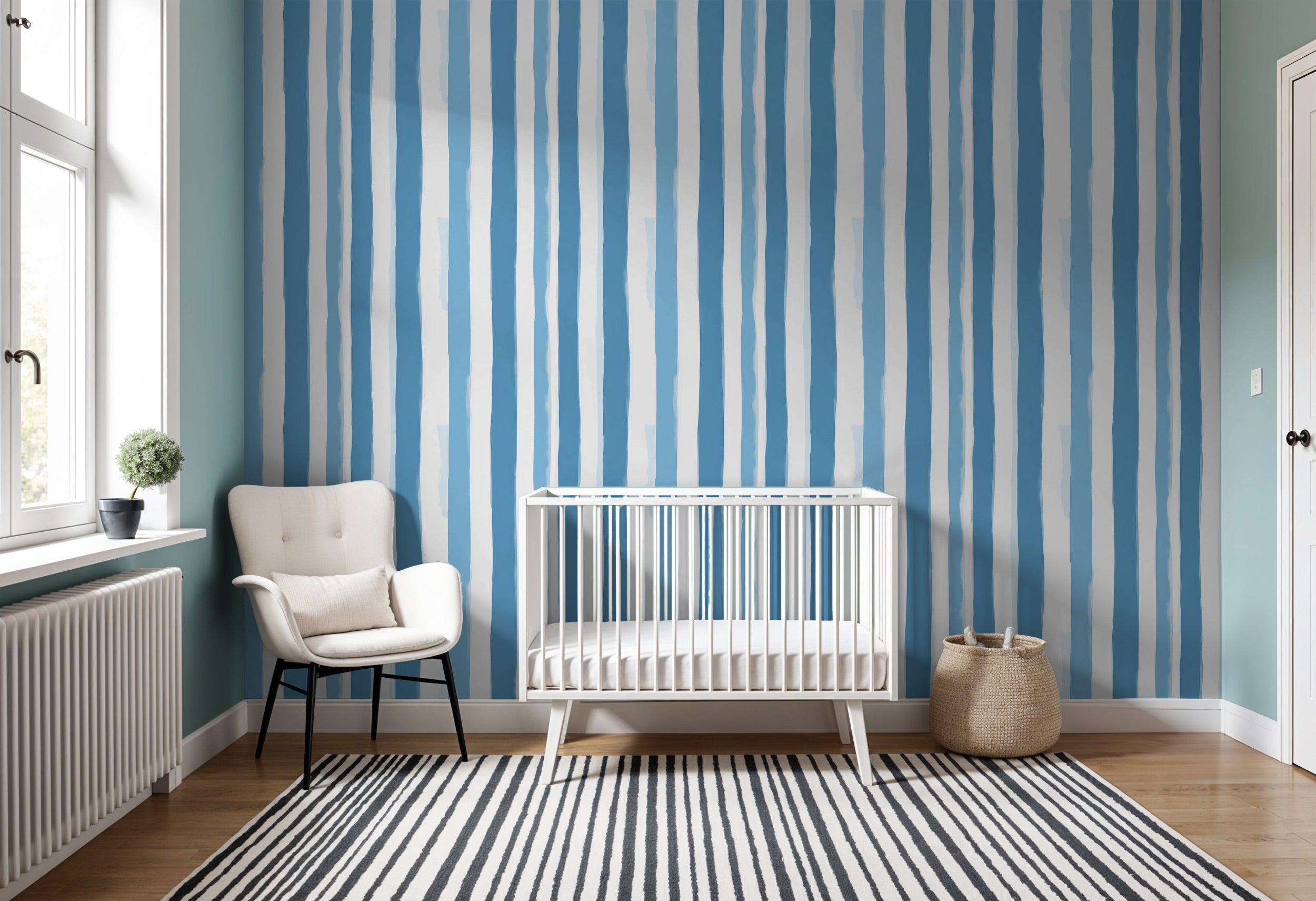 A nursery or bedroom with blue watercolor striped wallpaper, white crib, white chair, striped rug, and wicker basket beachy c