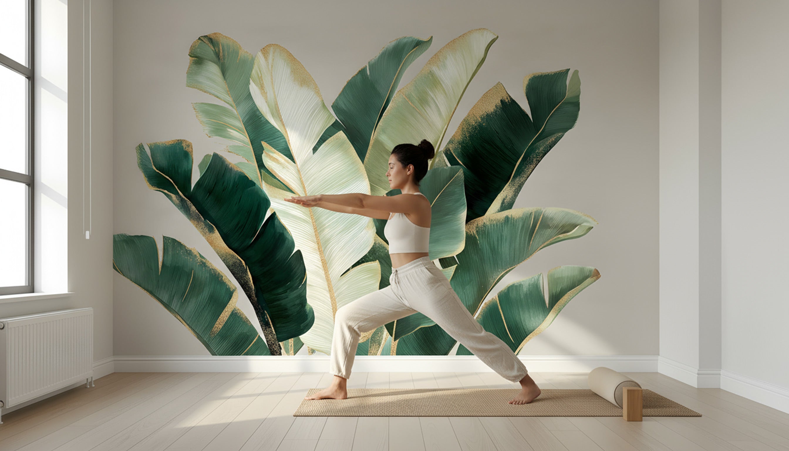 Yoga practitioner practicing warrior pose in a tropical banana leaf mural wall art with emerald green and gold accents in a bright living space